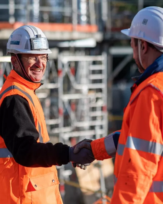 Construction workers shaking hands outside